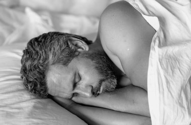 Beyaz yatakta uyuyan adam. Yatak odasında uyuyan seksi üstsüz adam. Latin kökenli olgun bir adam sabahları evde uyuyor. İyi uykular. Yatakta uyuyan adam. İnsanlar yatma vakti, dinlenme zamanı.