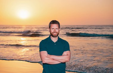 Denizde ya da okyanusta yakışıklı bir adam. Seyahat tatili. Denizde yürüyen adam, tropikal mevsimin tadını çıkar. Gün batımında Kafkasyalı yetişkinler gibi rahatla.