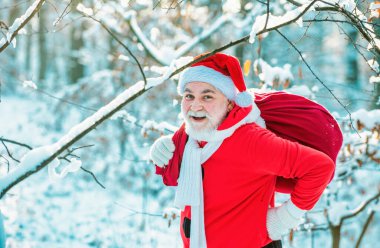 Kırmızı elbiseli Noel Baba Noel yolu boyunca yürüyor. Kocaman çantalı Noel Baba. Noel Baba dışarıdan hediyelerle gelir.