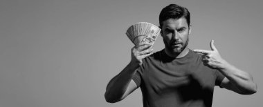 Başarılı bir iş adamı para sayıyor. Yakışıklı orta yaşlı adam 100 dolarlık banknotları tutuyor. Elinde para tutan adam. Kâr ve finansal başarı. Dolar nakiti olan zengin bir adam.