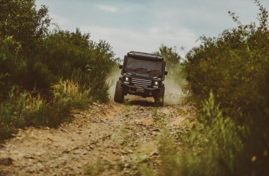 Tekerlekleri ve kumdaki toza dönüşen off-road 'u hareket ettir. Dağ yolunda off-road yolculuğu. Gezgin off-road aracı. Çamurlu bir arazide izler. Yol macerası. Macera seyahati