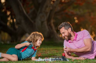 Baba ve oğul parkta birlikte satranç oynuyorlar. Akıllı çocuk, akıllı çocuklar.
