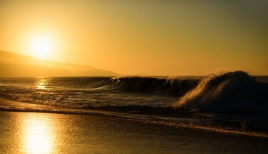 Altın gökyüzü ve okyanus suyu. Günbatımı ve okyanus ile soyut bir arkaplan. Deniz dalgaları arka planı. Deniz manzarasında gün batımı. Bulutlu dramatik günbatımı gökyüzü. Denizin üzerinde dramatik gün batımı