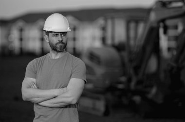 Endüstriyel alanda kazı yapan bir inşaat işçisi. Kask takan, buldozerli bir işçi. Mühendis, inşaat firmasında çalışıyor. Kazı ustabaşı ve traktör. Kazıcılı işçi