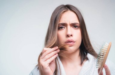Saç dökülmesi. Kadın saç dökülmesinden rahatsız. Sorunlu saçlı, izole edilmiş üzgün bir kızın portresi. Endişeli kız uzun hasarlı, sağlıksız saçları elinde tutuyor.