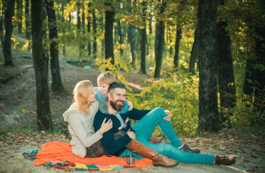 Doğada piknik. Mutlu bir aile battaniyede oturup sarılıyor. Köy ailesi. Mutlu aile anlamında. Doğayla bütünleşti. Aile günü konsepti. Çocuk dinlenirken mutlu bir aile.