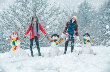 Güzel Kış Kızları grubu ve kardan adam. Öğrenci partisi ve Noel kutlaması. Kış Parkı 'nda kardan adamla eğlenen iki neşeli genç kadın. Mutlu Noeller ve mutlu yıllar.