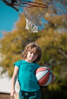 Mutlu küçük çocuk oyun alanında basketbol oynuyor.