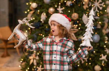 Mutlu noeller. Oğlum Noel kutlaması için evi hazırlıyor. Arka planda Noel ağacı var. Noel kış tatili konsepti. Noel oyuncakları