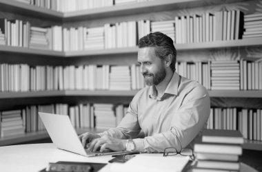 Kütüphanede kitabı olan bir öğretmenin portresi. Üniversite kütüphanesinde yakışıklı bir öğretmen. Öğretmenler Günü. Öğretmen ders veriyor. Kütüphanede öğretmen. Kitaplıktaki üniversite kütüphanesinde özel öğretmen.