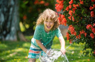 Çocuk eğleniyor. Komik çocuk doğal ortamda mutlu bir şekilde gülümsüyor. Küçük çocuk temiz havada eğleniyor. Komik olmak en büyük özelliklerimden biridir. Güneşli yaz gününde bahçedeki çiçekleri sulamak.