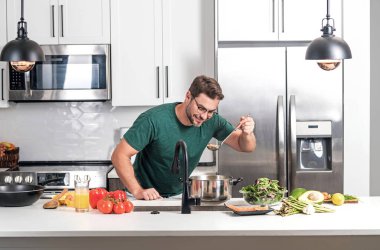 Evde yemek pişirmek. Mutfakta yemek hazırlayan adam. Erkek aşçı evde yemek hazırlıyor. Şef yemek yapıyor. Yemek pişiren adam, mutfak tenceresi, yemek tabağı. Adam mutfak içinde çorba hazırlıyor.