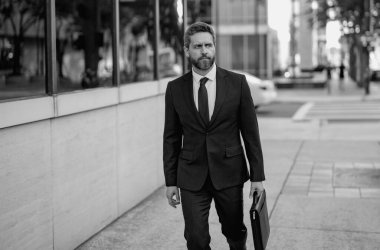 İş adamı hedefleri. İş adamlarının açık hava başarısı. Zarif takım elbiseli yakışıklı başarılı iş adamı. Evrak çantalı bir iş adamı şehirde yürüyor.