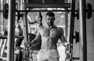 Handsome fit muscular caucasian man workout in the gym with weight pumping up muscles. Fitness and bodybuilding sport. Bodybuilder with dumbbells at gym, hard workout