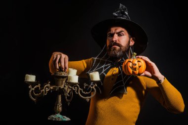 Cadılar Bayramı balkabaklı komik bir model. Cadılar Bayramı şapkalı olgun bir adamın kabaklı portresi. Şeker mi şaka mı? Cadılar Bayramı şapkalı korkunç hippi. Cadı şapkalı adam balkabağını tutuyor. Mutlu Cadılar Bayramı