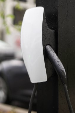 EV Car. Ulaşım aracı EV. Elektrikli araba. Elektrik kablosu takılı şarj istasyonu. Elektrikli araba şarj oluyor. Şarj istasyonundan şarj ediliyor.