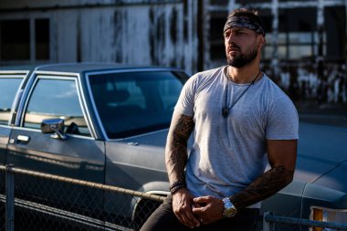 Yakışıklı hippi İspanyol modelin portresi. Sokaktaki seksi, modern adam. Moda erkeği sokak arka planında poz veriyor. Adam sokak çetesi, sosyal sorun. Suç şehri. Tehlikeli Amerikan Bölgesi