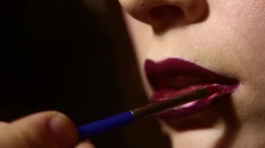 Moda ruju. Kırmızı dudaklı makro makyaj. Dudaklarına ruj süren genç ve güzel bir kadın. Dudak parlatıcısı yakın plan. Kadın dudakları için kozmetik. Rujla sürüyorum. Kırmızı ruj süren genç bir kadın.