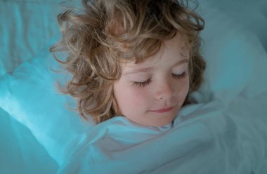 Çocuklar yatak odasında beyaz çarşaf ve yastıkla yatıyorlar. Gözler kapalı