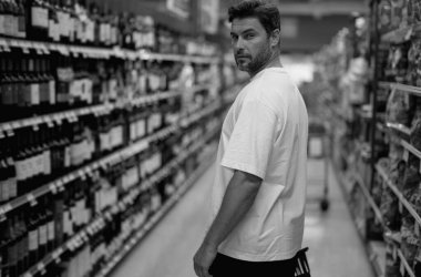 Şarap dükkanında içki şişelerini seçen bir adam. Adamın elinde alışveriş sepeti var. Mağaza, alışveriş, satış ve indirimler. Erkek alışverişçi. Elinde organik sebzeler ve meyvelerle alışveriş sepeti tutan adam.