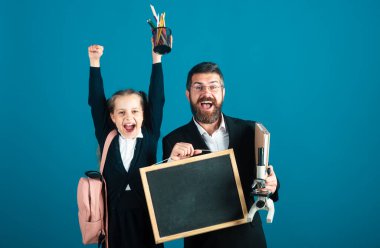 Okuldaki ilk günüm. Baba, öğretmen ve birinci sınıftaki küçük kız. Okula dön, üniformalı kız.