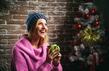 Kış mulled şarap içer. Bir genç güzel, kış gülümseyen kadın portresi. Yeni Yılınız Kutlu Olsun. Noel ağacı süslemeleri evde. Gülümseyen kadın Noel ağacı ev dekorasyon
