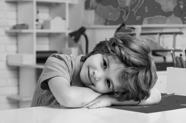 İlkokul öğrencisi içeride okuyor. Okul rüyası. Hayalperest okul çocuğu. Hayaller ve hayal gücü. Hayalci okul çocuğu suratı. Ev çalışması