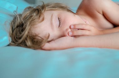 Ağzı açık uyuyan, horlayan küçük çocuklar. Çocuk yatak odasında beyaz çarşaf ve yastıkla uyuyor.