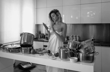 Sabahları modern mutfakta bir kadın. Sıcak mutfakta yemek pişiren genç bir kadın. Modern iç mekan, mutfak mobilyası.
