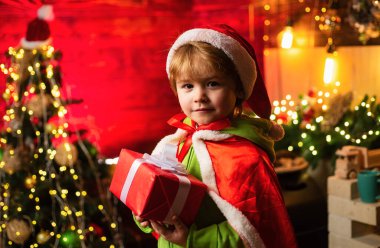 Çocuk kış tatilinin tadını çıkarıyor. Sevgi ve neşe dolu bir ev. Mutlu Noeller ve mutlu yıllar. En iyi dileklerimle. Aile tatili. Noel hediyesi. Sevimli küçük çocuk Noel ağacının yanında oynuyor..