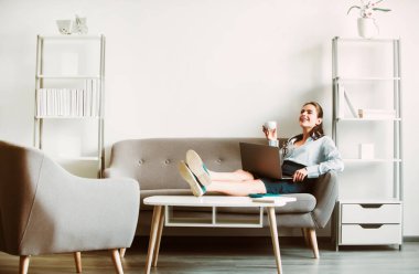 Break time concept. Joyful young web developer drinking coffee while taking break from work in office clipart