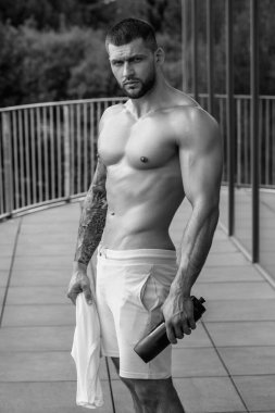 Kas yığını adam spor salonunda dambıllarla antrenman yapıyor. Spor salonunda poz veren kaslı yakışıklı bir adam. Kas sporcusu dambılı kaldırıyor. Spor kulübünde esneme, spor egzersizleri.