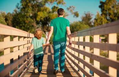 Arkadaş canlısı aile kavramı. Oğul ellerini uzatıyor baba. Arka manzara yakışıklı bir adam ve yakışıklı bir çocuk.