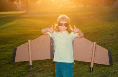 Pilot gözlüklü çocuk oyuncak jetpack ile oynuyor. Çocuk pilot astronot ya da uzay adamı uçmayı hayal eder. Karton kanatlarla uçan havacı çocuk.