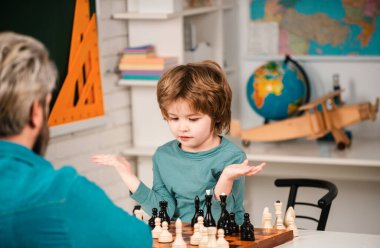 Satranç, başarı ve kazanmak. Eğitim oyunları, erken gelişim. Konsantre çocuk satranç stratejisi geliştiriyor, masa oyunu oynuyor