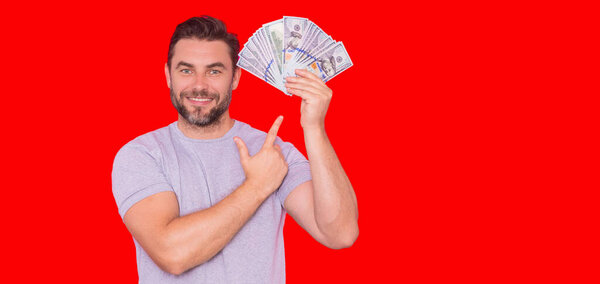 Человек, держащий наличные в долларовых банкнотах на изолированном красном баннере. Студийный портрет бизнесмена с банкнотами в долларах. Концепция долларовых денег. Карьерный бизнес. Баннер денежного доллара