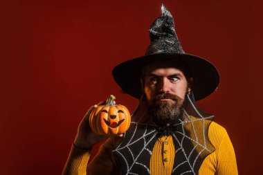 Cadılar Bayramı balkabaklı komik bir model. Cadılar Bayramı şapkalı balkabaklı insan portresi. Şeker mi şaka mı? Cadılar Bayramı şapkalı korkunç hippi. Cadı şapkalı adam balkabağını tutuyor. Baba, mutlu ol.