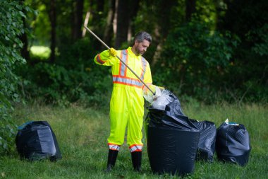 Dışarıdaki çöpleri toplayan gönüllü adam. Ekoloji konsepti. Çevre kirliliği. Dünya Günü. Çöp tenekelerini geri dönüşümle temizleyin. Doğa temizliği. Çevre plastik kirliliği