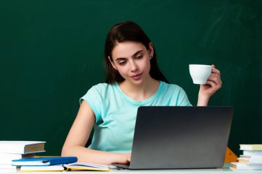 Öğrenci kız sınıfta ders çalışıyor. Öğrenci kız materyali anlamak için çok çalışıyor. Öğrenci sınıfta kahve içiyor. Üniversitede kahve molası. Öğrenci kız kahve fincanı tutuyor.