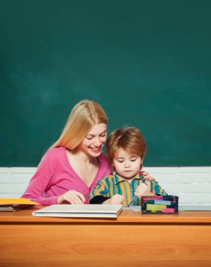 Anaokulu öğretmeni sınıfta küçük bir öğrenciye ders veriyor.