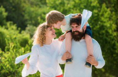 Baba oğlunu parka geri götürüyor. Mutlu aile ve küçük oğlu mavi gökyüzünde oynuyorlar. Çocukluk. Baba, anne ve oğul kamp yapıyor.