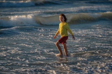 Happy child playing in the sea. Kid having fun outdoors. Summer vacation and healthy lifestyle concept. Cute kids having fun on beach in summer. Happy child playing in the sea. Summer vacation