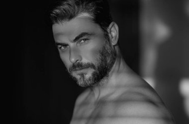 Yüzünde nemlendirici krem olan, izole bir geçmişi olan yakışıklı bir adamın güzel portresi. Cilt rutini kavramı. Erkek saç kesimi, bıyık ve sakal. Erkek güzeli. Traş, saç şekillendirme.