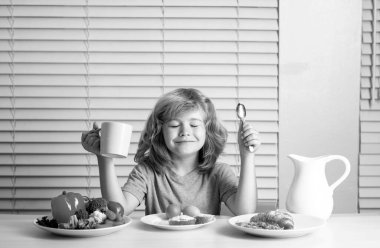 Çocuk sağlıklı sebze yiyor. Süt, meyve ve sebzeli kahvaltı. Öğle ya da akşam yemeği sırasında çocuk yemek