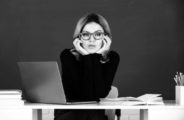 Portrait of teacher at school with computer laptop in classroom on blackboard