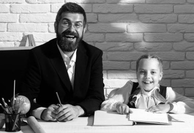 Küçük öğrenci kız mükemmel bir notla mutlu. Şirin bir anaokulu çocuğu ve sınıfta gülümseyen bir öğretmen. Okul malzemeleriyle masasının yanında gülen surat ifadesiyle sevimli öğrenci kız.