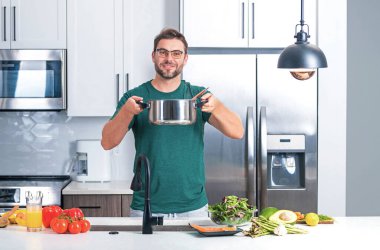 Adam mutfakta yemek pişiriyor. Aşçı şefi tencereli bir yemek hazırlıyor. Menü tarifi sağlıklı yemek. Adam modern mutfakta yemek pişiriyor. Olgun bir adam mutfakta yemek hazırlıyor.