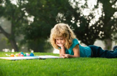 Çocuk çizimi. Bahçede ya da bahar parkında resim çizen mutlu çocuk portresi. Çocuklar dışarıda kalemle çizim yapıyorlar.