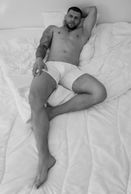 Yatakta yatan yakışıklı çıplak adam manzarası. Geceleri yatakta yatan yakışıklı genç adamın en iyi görüntüsü. Yatakta yatan kaslı yakışıklı adam. Yatakta yatan adam, seksi vücut.