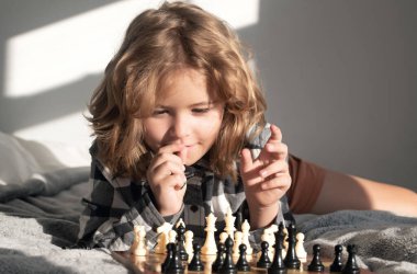 Little kid play chess. Thinking child. Chess game with children at home